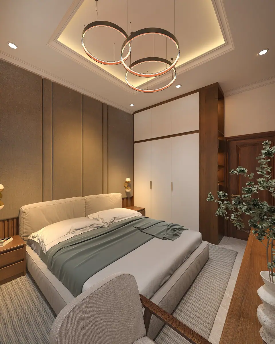 Giường bọc vải tông be, chăn xanh xám dưới cụm đèn thả vòng tròn